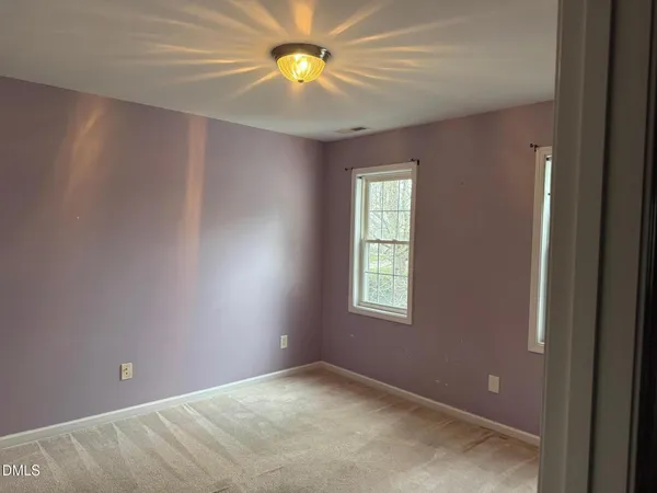 an empty room with windows and chandelier fan