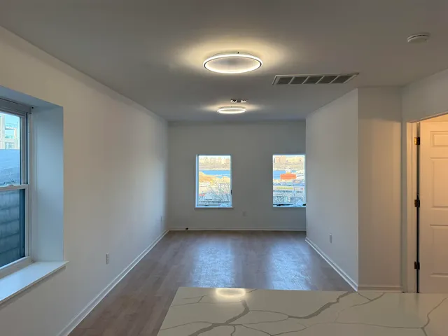an empty room with wooden floor and windows