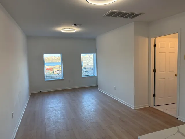 an empty room with wooden floor and windows