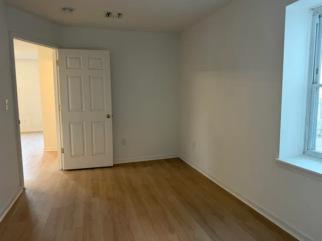 a view of empty room with wooden floor and fan