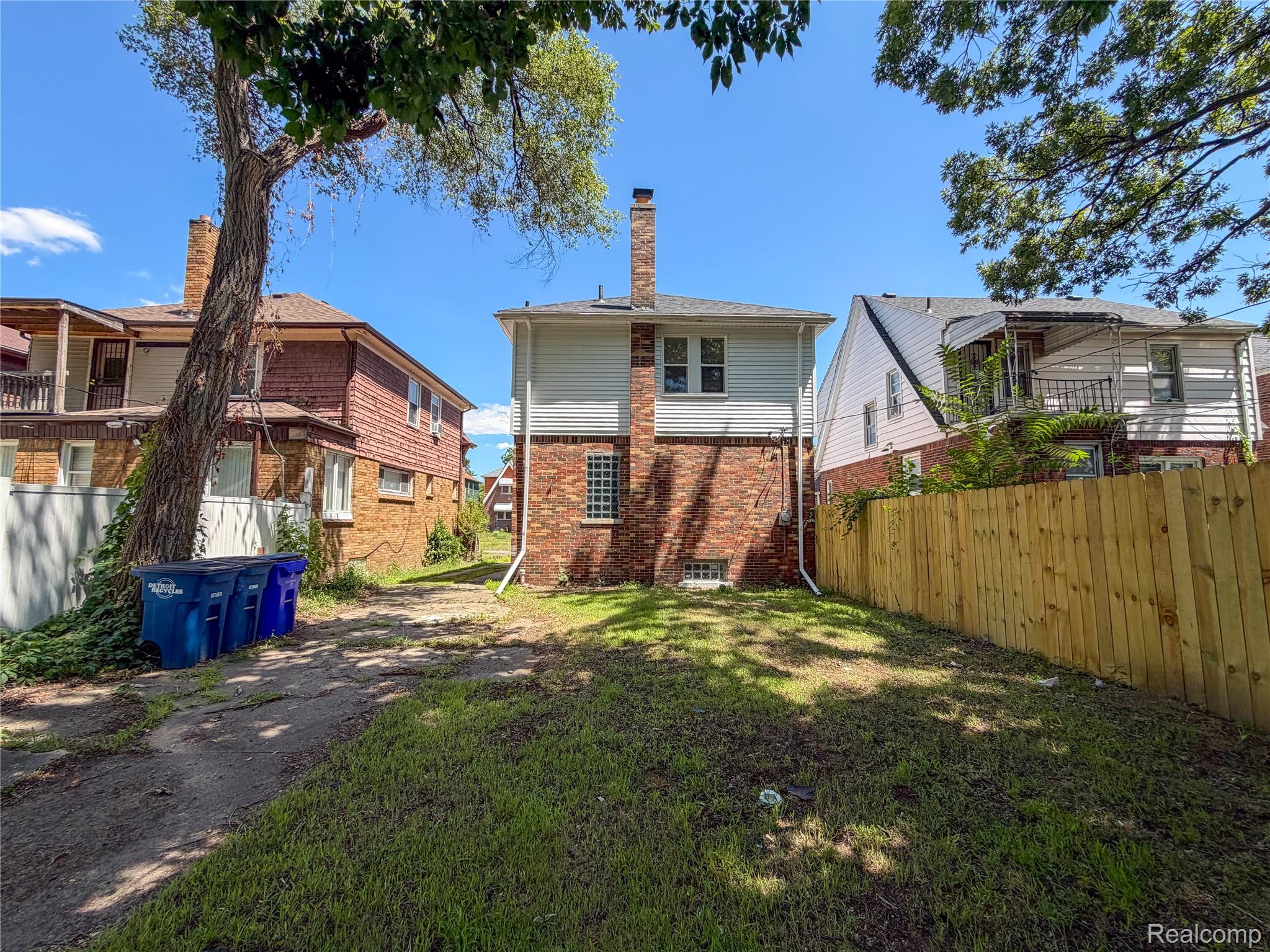 18217 Prairie Street Detroit, MI 48221 - Photo 28 of 34 Rear exterior featuring a brick and siding facade, a prominent chimney, and a new wood privacy fence