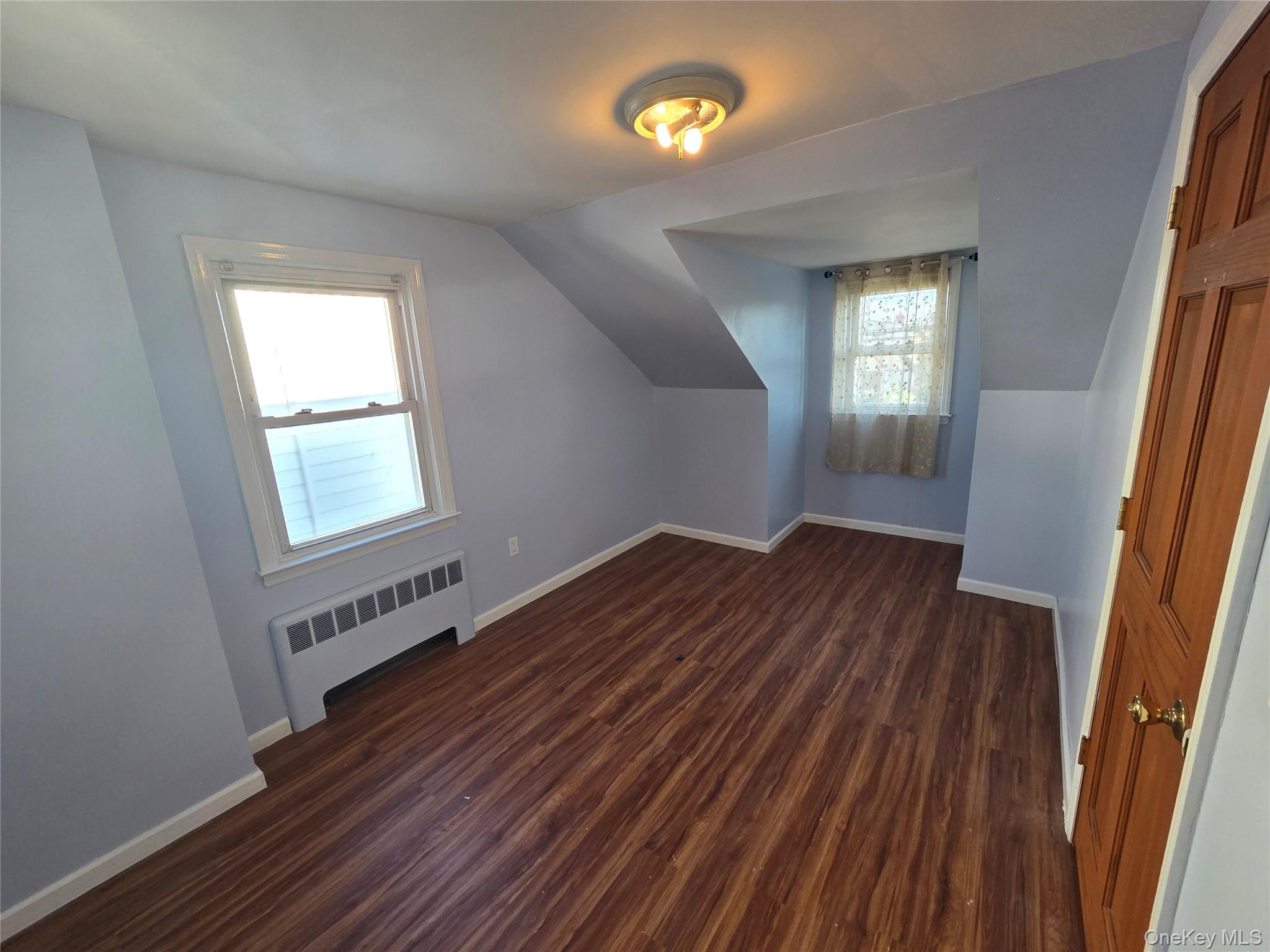 220 Raff Avenue Mineola, NY 11501 - Photo 17 of 22 Bedroom - Additional living space featuring dark wood-style flooring, radiator heating unit, and lofted ceiling