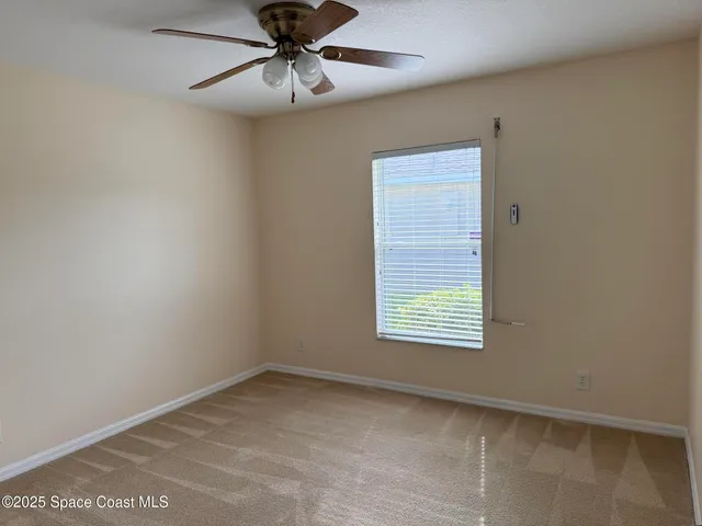 an empty room with a window and ceiling fan