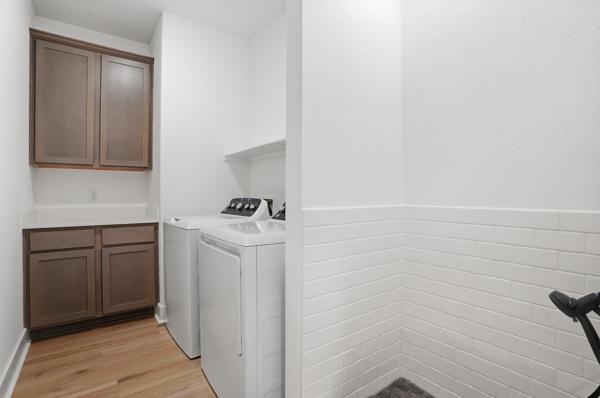 201 Prodigal Way Kyle, TX 78640 - Photo 12 of 22 The laundry area features ample cabinetry, a white countertop, and wood flooring