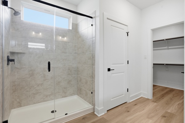 201 Prodigal Way Kyle, TX 78640 - Photo 16 of 22 The bathroom features a spacious walk-in shower with clear glass enclosure, a tiled shower interior with a built-in niche, and a window above the shower