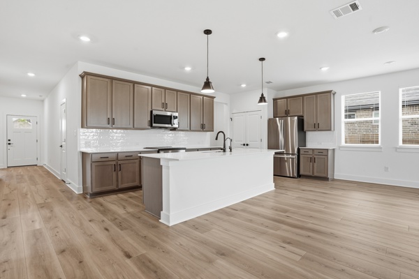201 Prodigal Way Kyle, TX 78640 - Photo 18 of 22 The property features an open-concept kitchen with light-colored flooring, recessed lighting, and pendant lights over a central island
