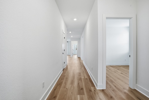 201 Prodigal Way Kyle, TX 78640 - Photo 6 of 22 The property features a hallway with light wood flooring, white walls, and recessed lighting