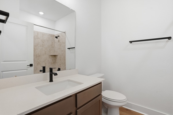 201 Prodigal Way Kyle, TX 78640 - Photo 8 of 22 Bathroom featuring a vanity with a white countertop and an integrated sink, a dark bronze faucet, and a toilet