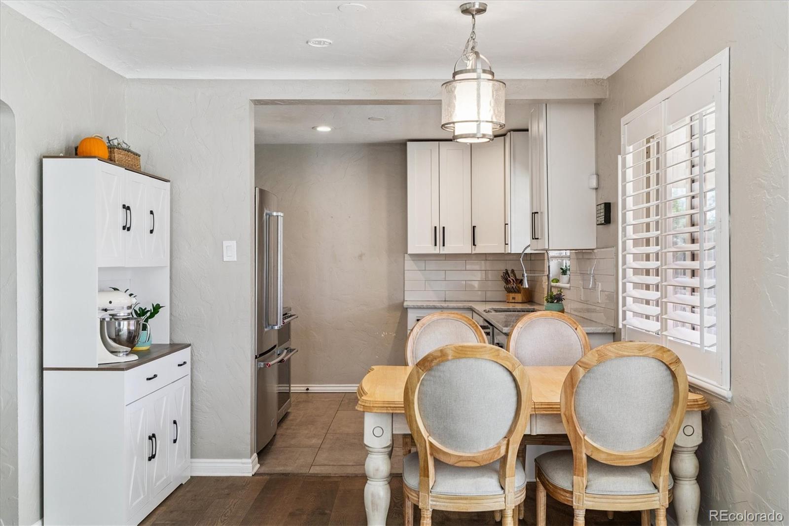 2660 Kearney Street Denver, CO 80207 - Photo 10 of 35 a kitchen with stainless steel appliances kitchen island granite countertop a table chairs and chandelier