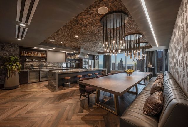 a living room with stainless steel appliances furniture a chandelier and kitchen view