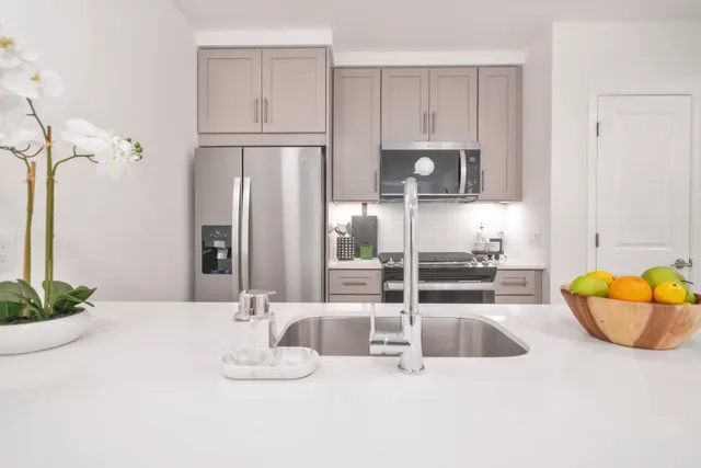 a kitchen with stainless steel appliances kitchen island granite countertop a refrigerator and a sink