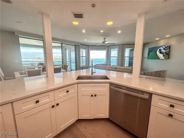 a large living room with large windows and view of kitchen
