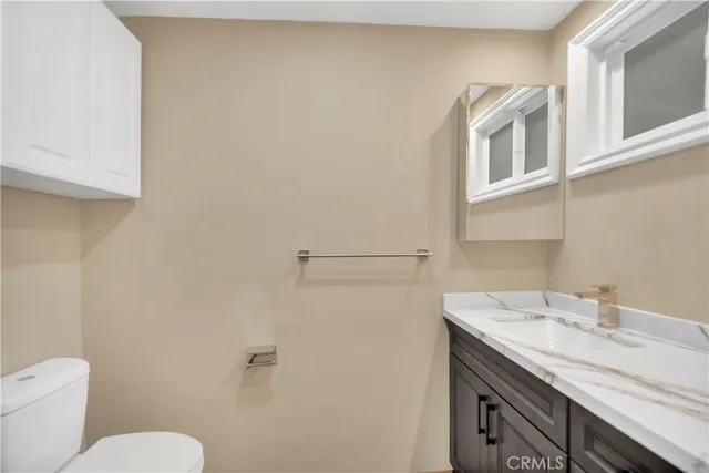 a bathroom with a granite countertop sink and a toilet
