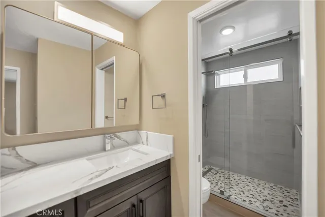 a bathroom with a granite countertop sink a mirror and a shower