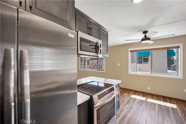 a kitchen with stainless steel appliances granite countertop a refrigerator a stove and a sink with wooden floor