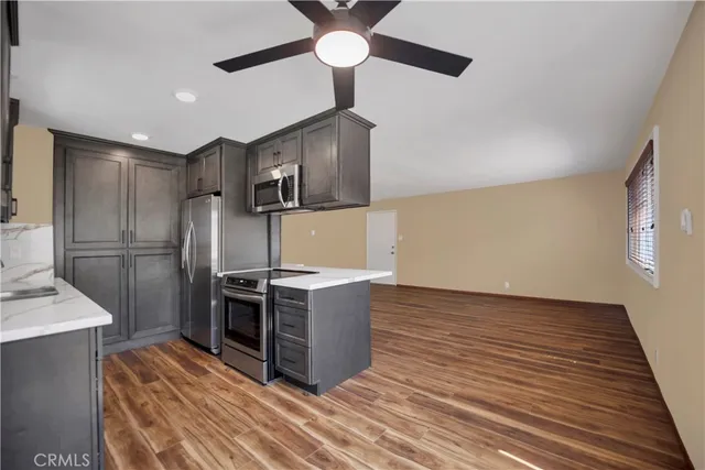 a kitchen with stainless steel appliances a stove a refrigerator and a sink with wooden floor