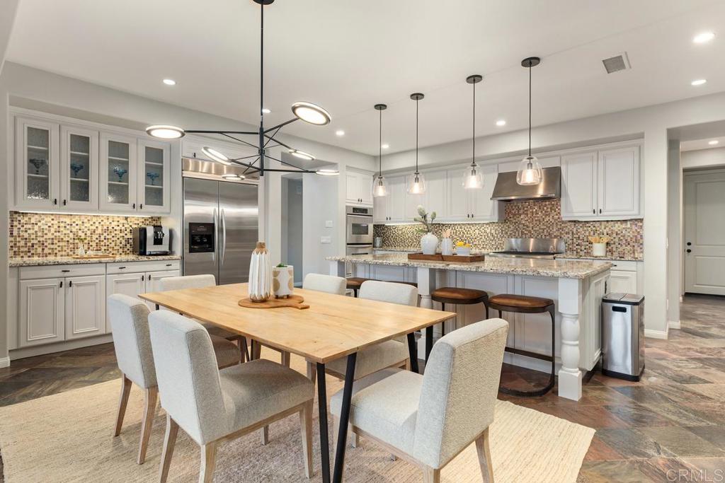7627 Circulo Sequoia Carlsbad, CA 92009 - Photo 12 of 72 a kitchen with kitchen island a dining table chairs and white cabinets