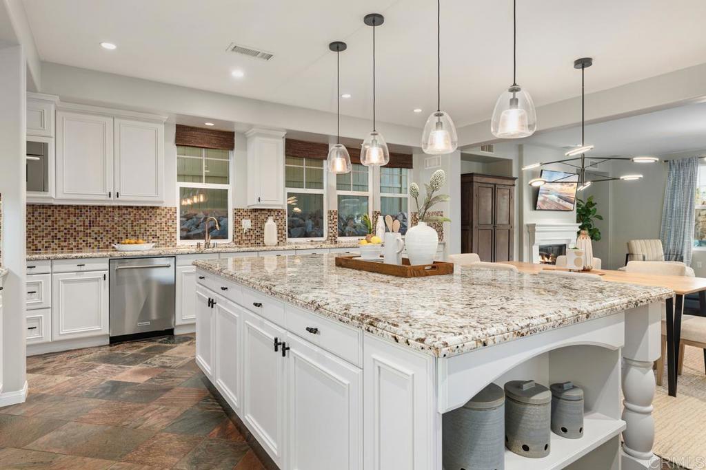 7627 Circulo Sequoia Carlsbad, CA 92009 - Photo 16 of 72 a kitchen with kitchen island granite countertop a table chairs and white cabinets