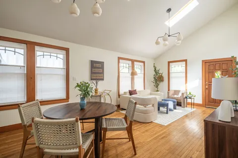 a dining room with furniture a large window and wooden floor