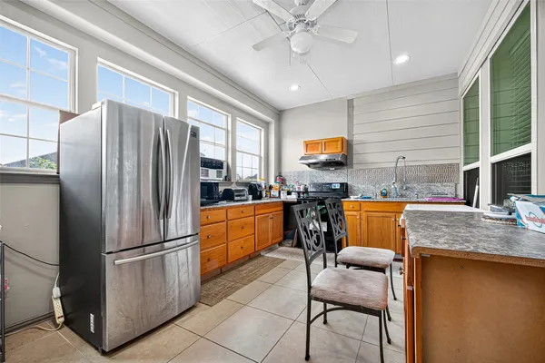 a kitchen with stainless steel appliances granite countertop a refrigerator a stove a sink a dining table and chairs