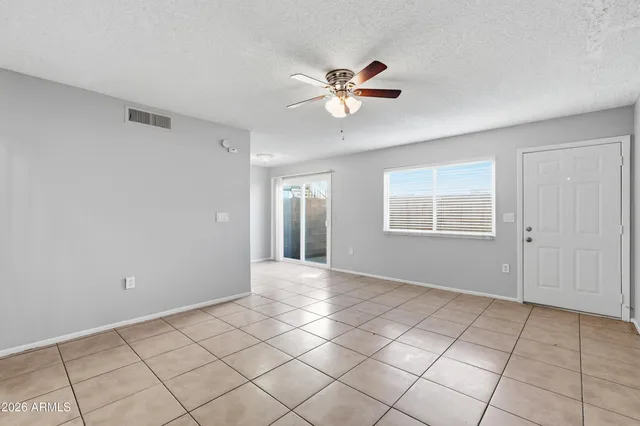 a view of an empty room with window and chandelier fan