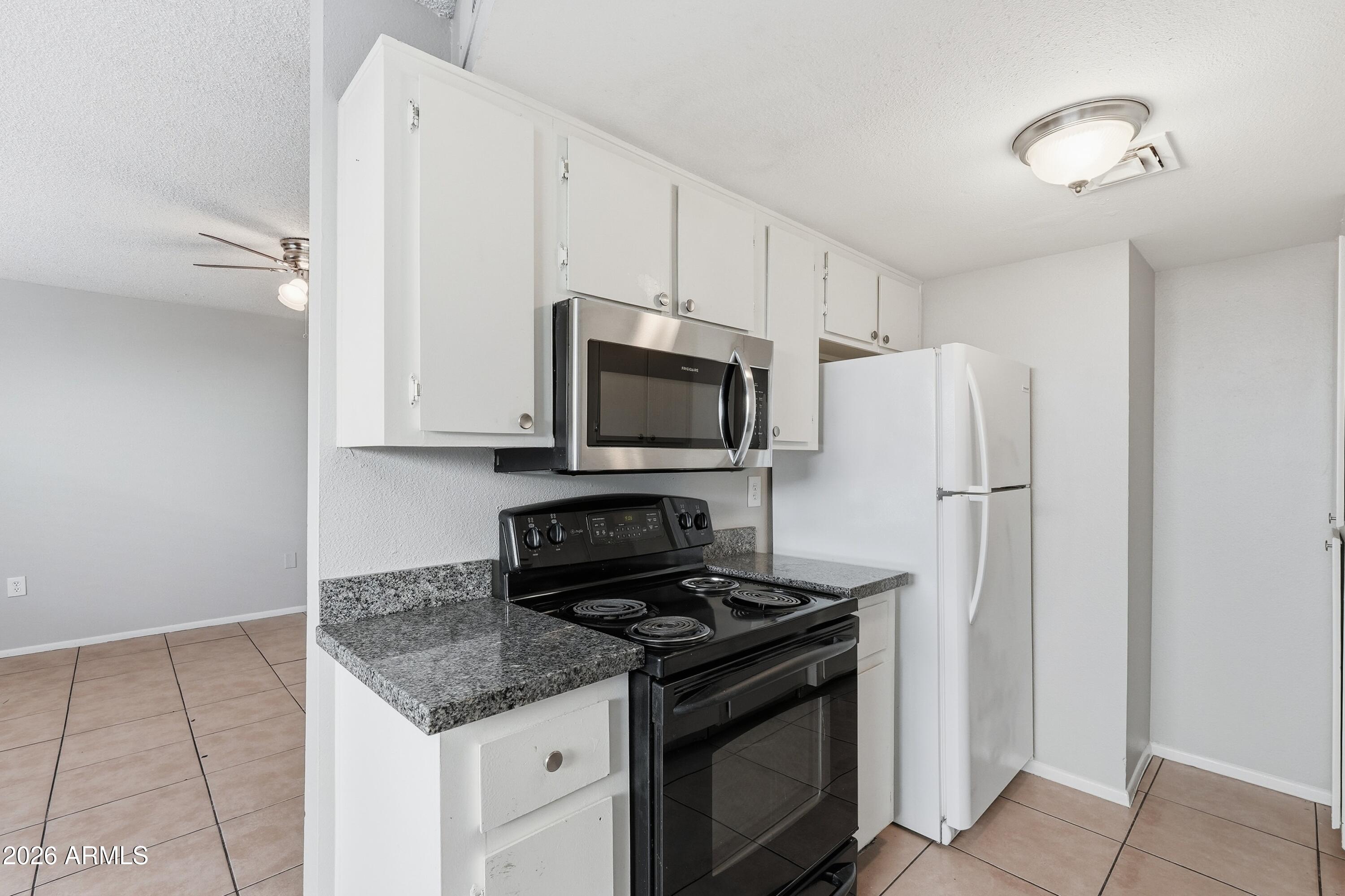 860 East Brown Road, Unit 29 Mesa, AZ 85203 - Photo 26 of 54 a kitchen with stainless steel appliances granite countertop a refrigerator stove and microwave