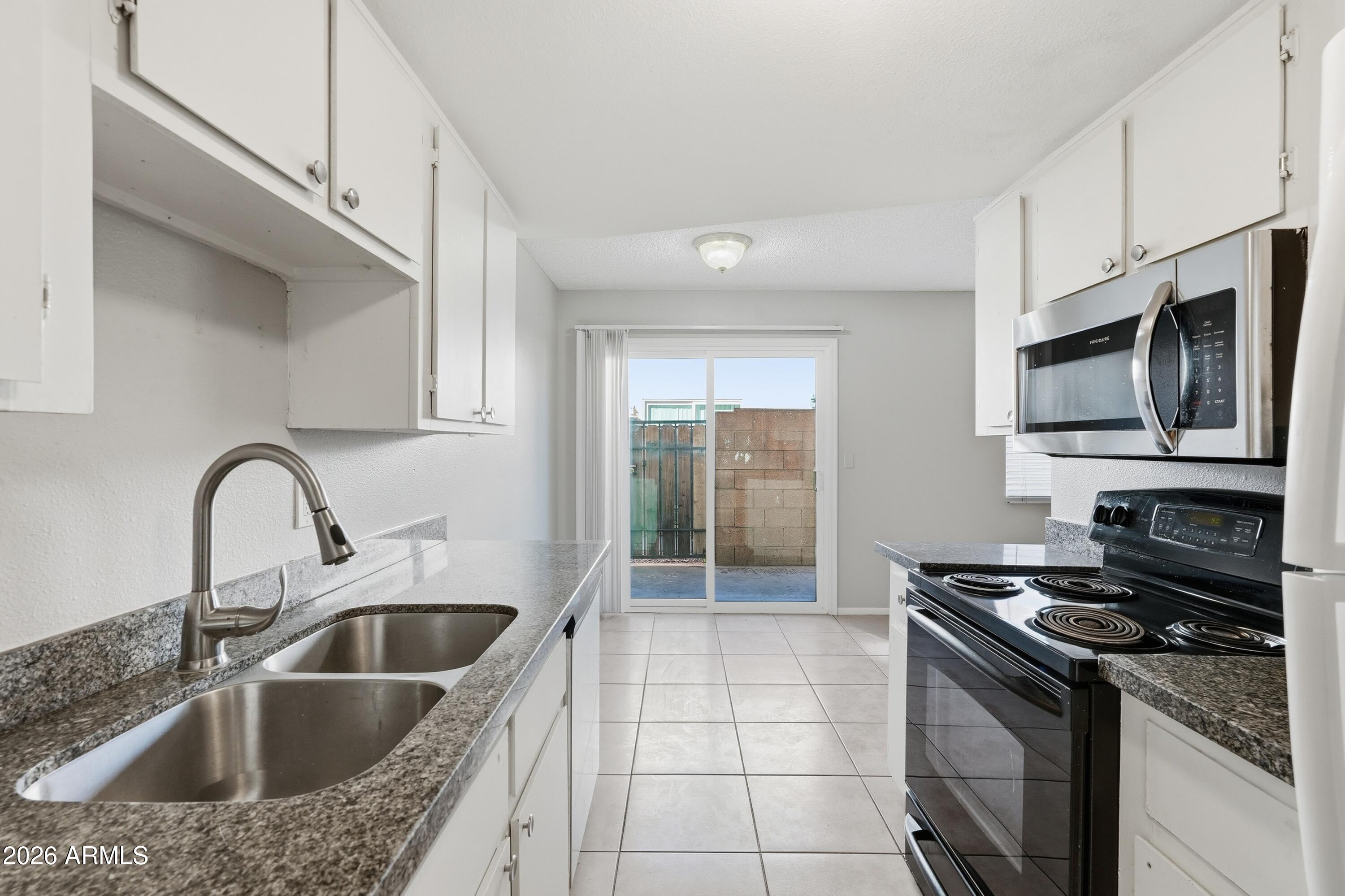 860 East Brown Road, Unit 29 Mesa, AZ 85203 - Photo 27 of 54 a kitchen with stainless steel appliances granite countertop a sink a stove and a refrigerator