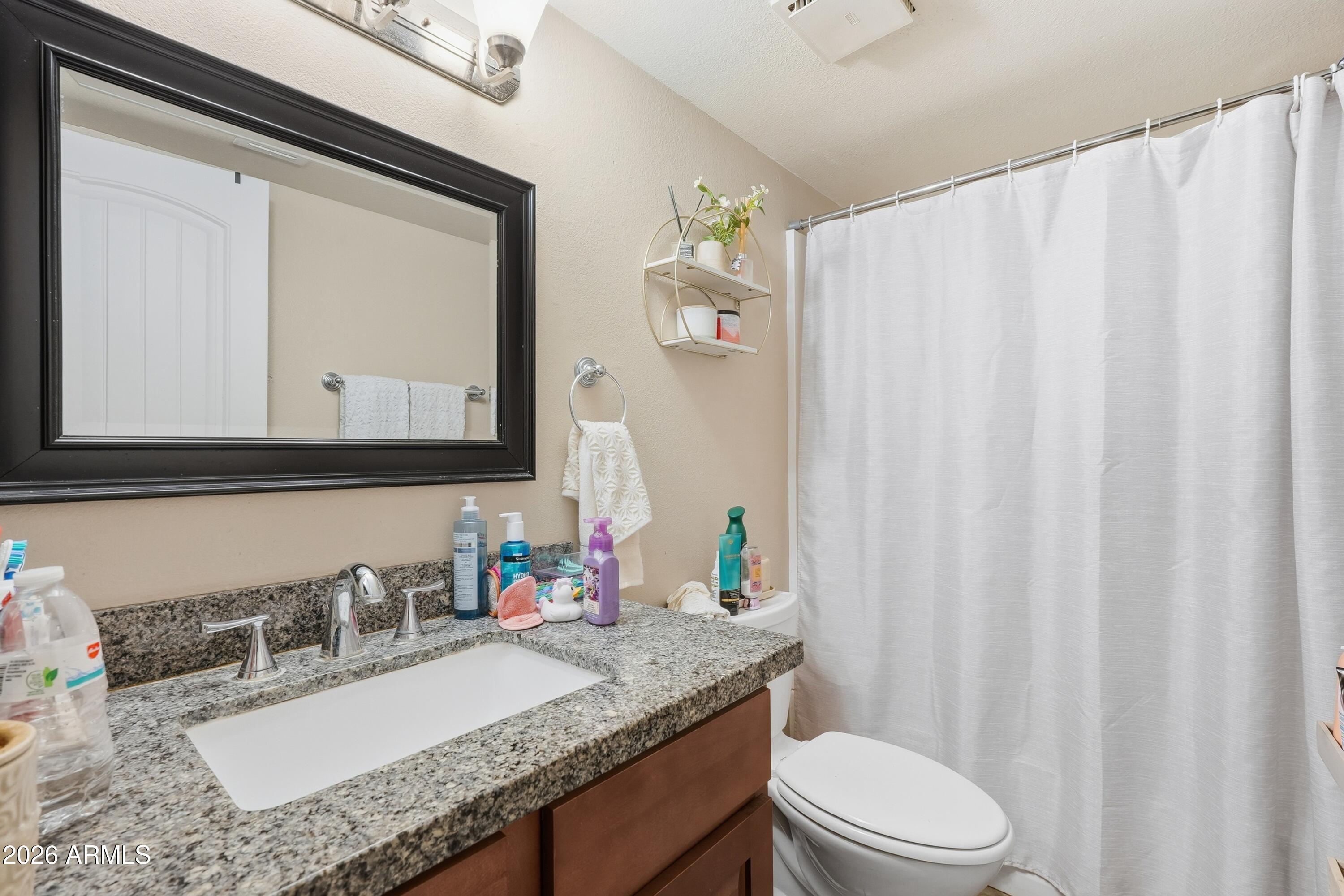 860 East Brown Road, Unit 29 Mesa, AZ 85203 - Photo 46 of 54 a bathroom with a granite countertop sink vanity mirror and a toilet