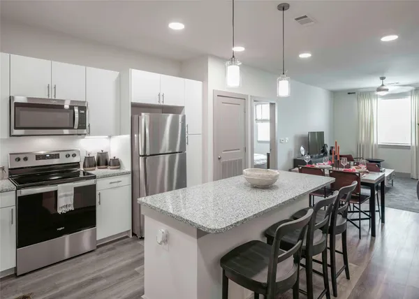 a kitchen with granite countertop a table chairs microwave and refrigerator