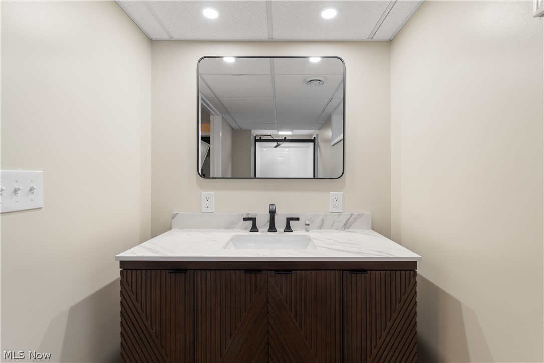 1075 Northeast River Road Lake Milton, OH 44429 - Photo 27 of 34 Modern vanity featuring a patterned wood-finish cabinet, white countertop with integrated sink, and matte black faucet