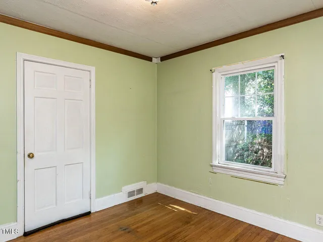 a view of an empty room with window and wooden floor