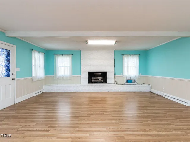 a view of a bedroom with wooden floor and white walls
