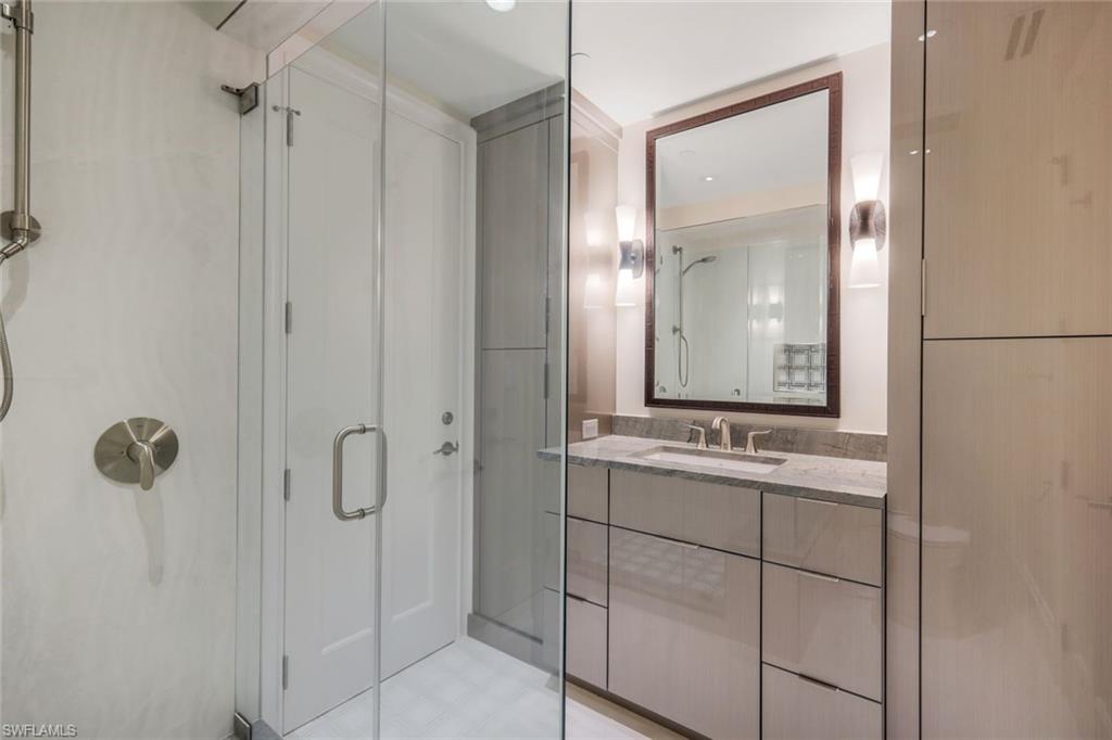 285 Grande Way, Unit 1006 Naples, FL 34110 - Photo 14 of 46 a bathroom with a granite countertop sink a mirror and shower