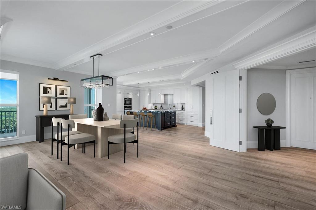 285 Grande Way, Unit 1006 Naples, FL 34110 - Photo 3 of 46 a view of a dining room and livingroom with furniture wooden floor a rug a painting and a chandelier