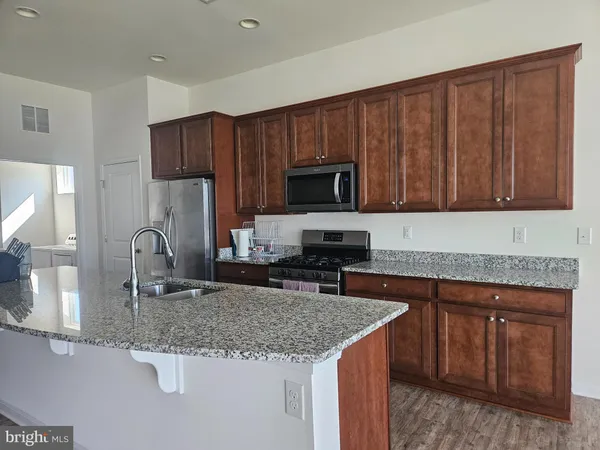 a kitchen with kitchen island granite countertop a sink stove and microwave