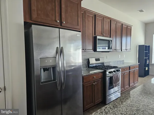 a kitchen with stainless steel appliances granite countertop a stove a refrigerator and a microwave
