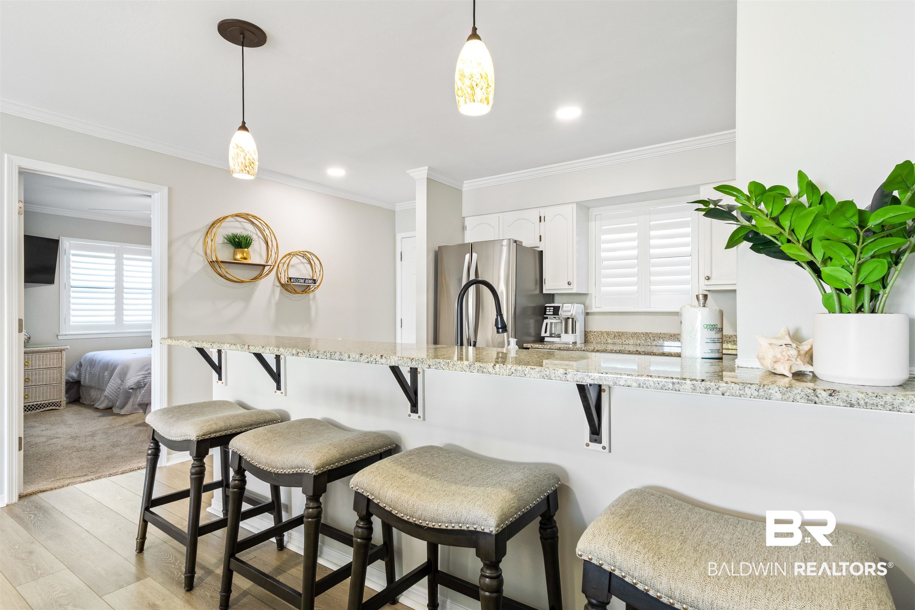 25861 Canal Road, Unit 3 Orange Beach, AL 36561 - Photo 8 of 40 Kitchen featuring white cabinets, light wood-style floors, freestanding refrigerator, crown molding, and light stone counters