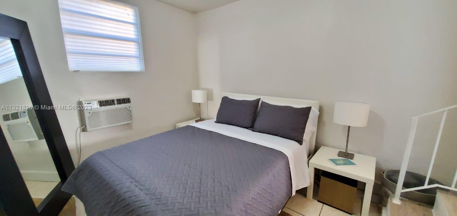 275 Northwest 46th Street, Unit B Miami, FL 33127 - Photo 6 of 9 a bedroom with a bed a mirror and a window