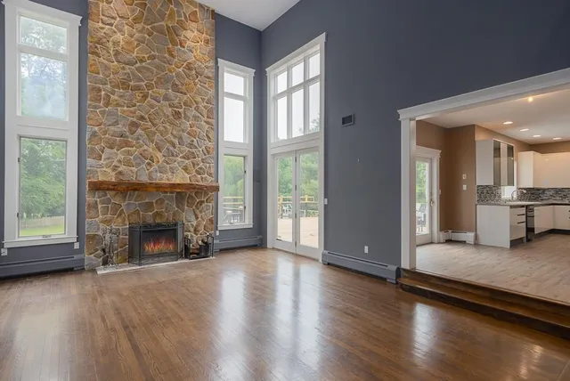 an empty room with wooden floor fireplace and windows