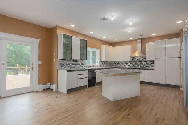 a large kitchen with a large counter top a sink stainless steel appliances and cabinets