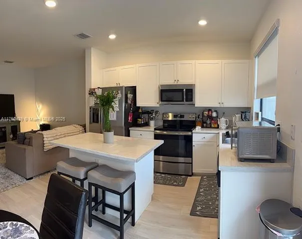 a kitchen with stainless steel appliances a stove a sink a refrigerator a microwave a dining table and chairs