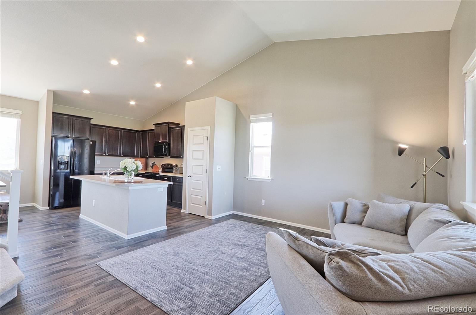 8376 Brandywine Avenue Frederick, CO 80504 - Photo 4 of 31 a living room with stainless steel appliances kitchen island granite countertop a couch and wooden cabinets
