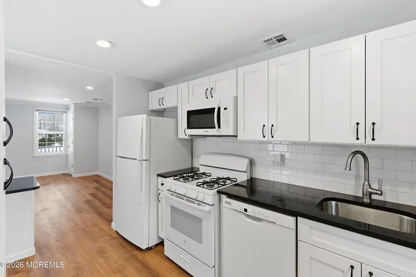 a kitchen with granite countertop a sink stove and refrigerator