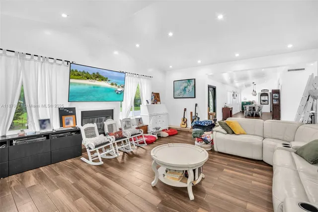 a living room with furniture a large window and wooden floor