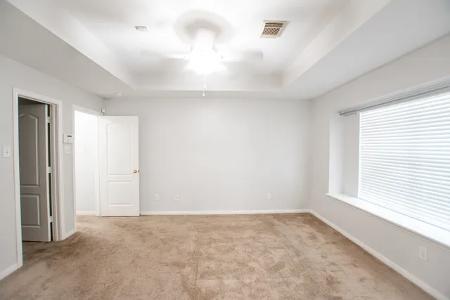 an empty room with a window and a fan