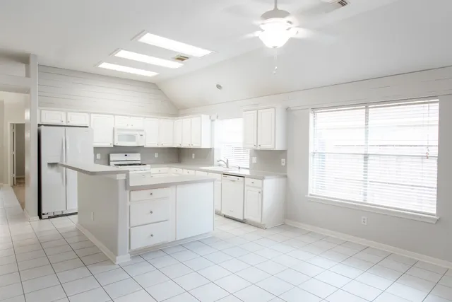 a kitchen with white cabinets and window