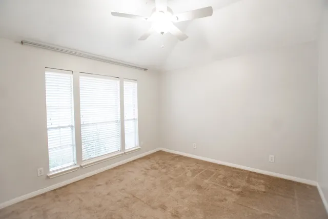an empty room with windows and ceiling fan