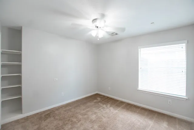 an empty room with a window and a fan