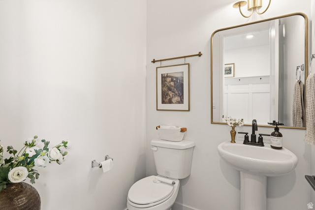 870 North Ada Loop Lehi, UT 84048 - Photo 18 of 51 Pedestal sink with matte black faucet, wall-mounted mirror with brass frame, and a brass-finish wall sconce
