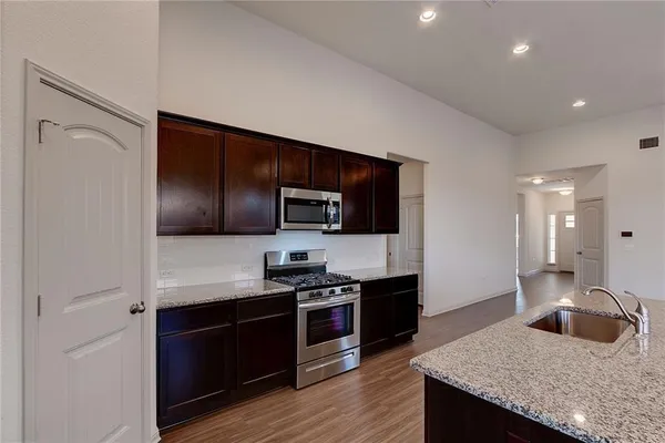 a kitchen with kitchen island granite countertop stainless steel appliances and wooden cabinets
